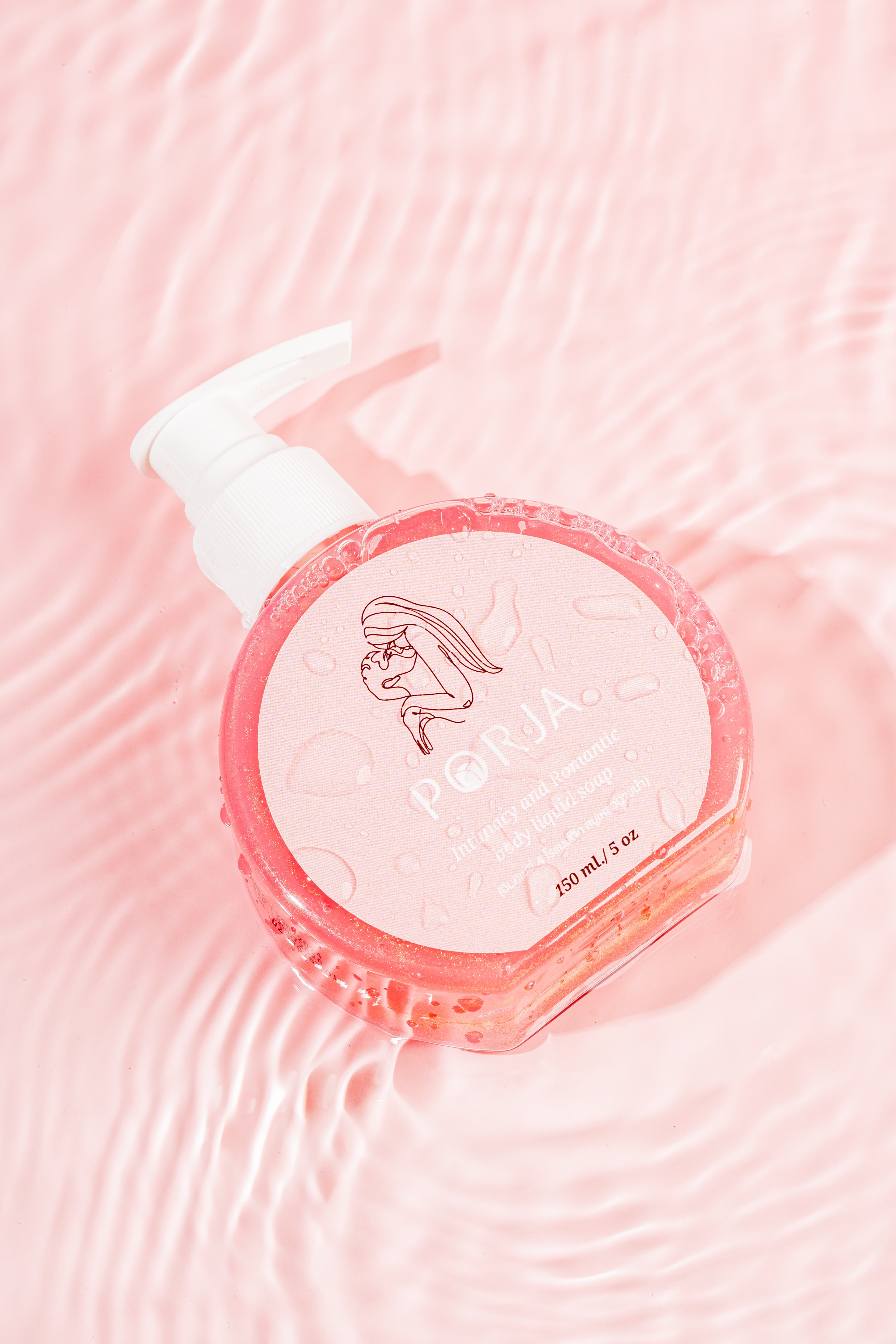 ขวดสบู่เหลว PORJA สีชมพูพร้อมหัวปั๊ม วางอยู่บนผิวน้ำใสที่เป็นระลอกคลื่น